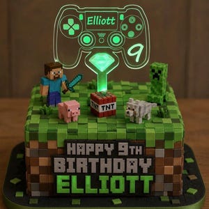 May include: A square cake decorated with green and brown pixelated blocks, featuring Minecraft character figurines, a TNT block, and a glowing acrylic cake topper shaped like a game controller with the name Elliott and the number 9.