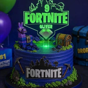 May include: A round blue frosted cake decorated with a purple llama figure, a wooden treasure chest, and two pickaxes. The cake features a glowing green acrylic topper with the text 9 FORTNITE OLIVER and a black Fortnite logo plaque.