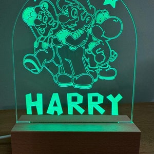 May include: Green illuminated acrylic sign with a silhouette of Mario, Luigi, and Yoshi characters from the Super Mario Bros. video game. The sign also has the name "HARRY" in block letters.