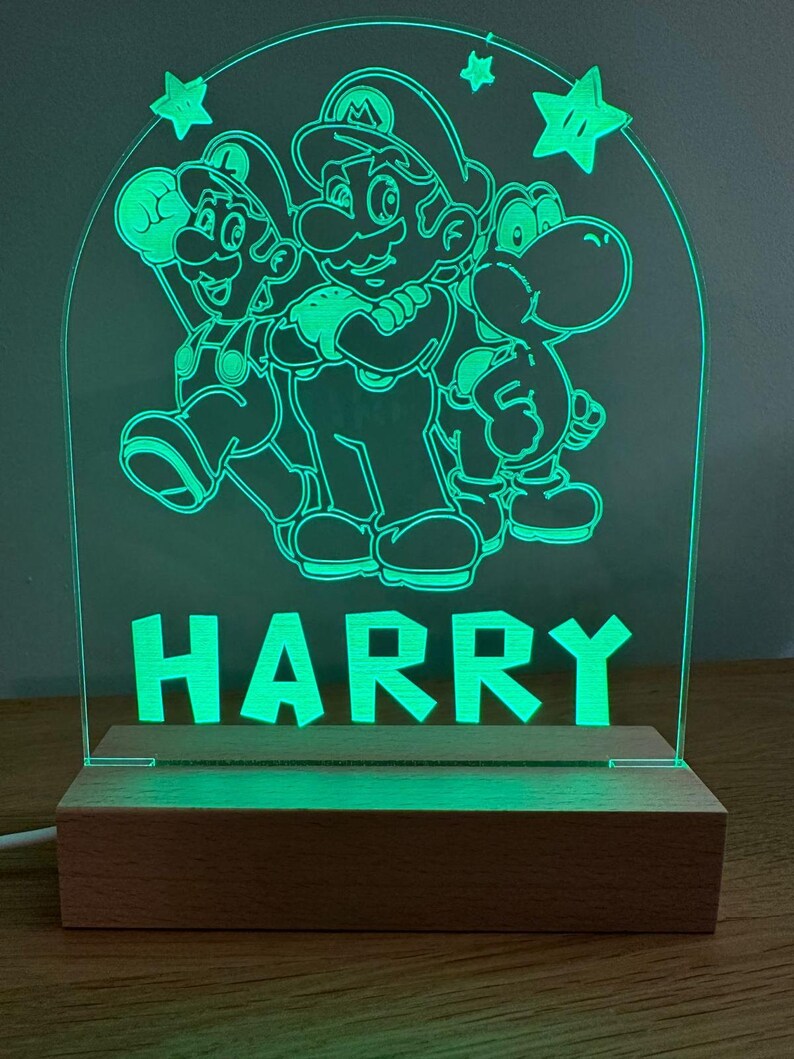 May include: Green illuminated acrylic sign with a silhouette of Mario, Luigi, and Yoshi characters from the Super Mario Bros. video game. The sign also has the name "HARRY" in block letters.