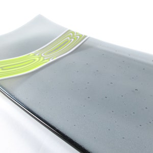 May include: A gray glass serving dish with a wavy edge and a band of green and white wavy lines.