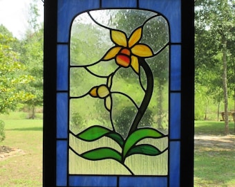 May include: A stained glass window panel depicting a yellow orchid with green leaves and a blue background.