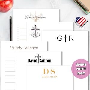 May include: A collection of white stationery with various designs and text, including "David Saffron," crosses, and initials. A pink circle with "SHIPS NEXT DAY" is visible. A pen and an apple are also present.