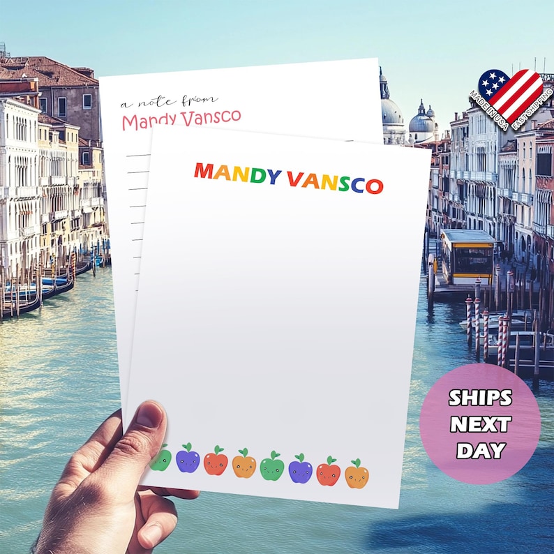 Pu&ograve; includere: Un blocco note bianco con un bordo di mele arcobaleno. Il blocco note ha il testo "a note from Mandy VanscO" e "MANDY VANSCO" stampato su di esso.