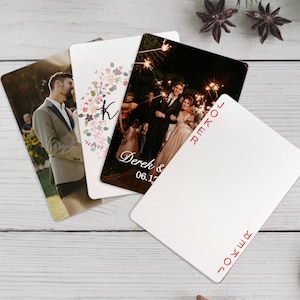 K&ouml;nnte beinhalten: Vier Hochzeitseinladungskarten mit unterschiedlichen Designs. Eine Karte zeigt einen Blumenkranz mit dem Buchstaben K in der Mitte. Eine andere Karte zeigt ein Foto eines Paares, das Wunderkerzen h&auml;lt. Die dritte Karte zeigt ein Foto eines Paares in Abendgarderobe. Die vierte Karte ist leer mit dem Wort "JOKER" in rot oben und unten gedruckt.