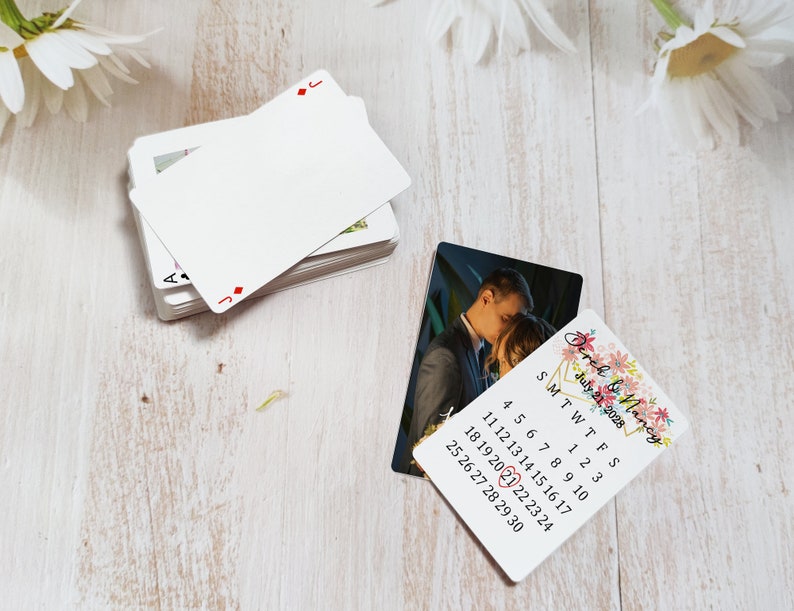 K&ouml;nnte beinhalten: Eine Save-the-Date-Karte f&uuml;r eine Hochzeit mit einem floralen Design und einem Foto eines Paares. Die Karte enth&auml;lt einen Kalender mit dem hervorgehobenen Datum 21. Juli 2028.