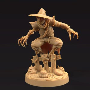 May include: A tan-colored figurine of a scarecrow with a wide-brimmed hat, tattered clothing, and long, claw-like fingers. It is posed on a wooden fence with pumpkins at its base, perfect for Halloween decor.
