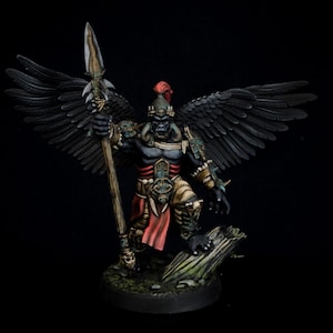 Könnte beinhalten: Eine schwarz und grün bemalte Miniaturfigur eines geflügelten Kriegers, der eine Lanze hält. Die Figur trägt einen rot-goldenen Helm und eine Rüstung. Die Figur steht auf einem Sockel mit einer grün-braunen Textur.