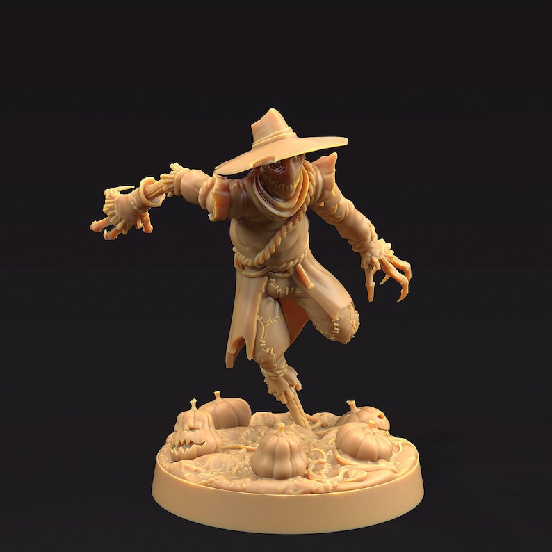 May include: A tan-colored figurine of a scarecrow with a wide-brimmed hat, tattered clothing, and straw-like hands. The scarecrow is posed with one leg raised, standing on a base with pumpkins and vines. A Halloween-themed decorative item.