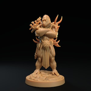 Op de afbeelding: Een bruin miniatuurbeeldje van een gorilla-achtig wezen dat een gehelmde helm en harnas draagt, met een wapen in zijn rechterhand. Het beeldje staat op een ronde basis.