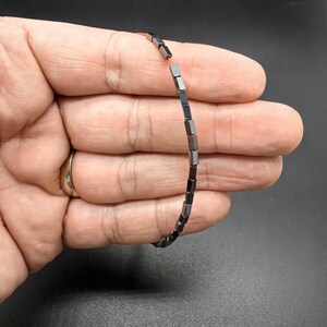 Peut inclure: Un bracelet en hématite noire avec des perles carrées.