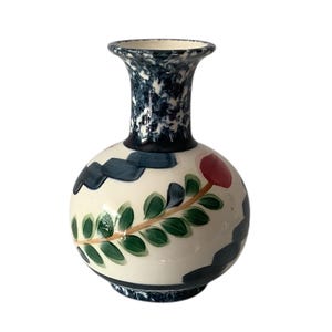 May include: A hand-painted ceramic vase with a round body and a flared neck. The vase features a cream-colored base with dark blue and green painted accents, and a red floral design. The vase is approximately 7 inches tall.