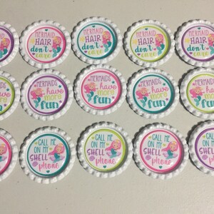 May include: Twenty white bottle caps with colorful mermaid themed designs. The designs include mermaids with the text "Mermaid Hair don't care", "Mermaids have more fun", and "Call me on my shell phone".