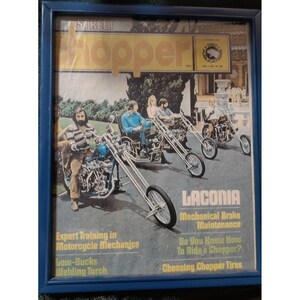 May include: A framed vintage Street Chopper magazine cover featuring a person on a custom motorcycle in the foreground, with two other motorcycles and riders in the background. The text includes titles like Laconia, Mechanical Brake Maintenance, and Expert Training in Motorcycle Mechanics.
