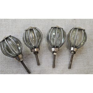 May include: Four spherical cabinet knobs featuring clear, ribbed glass centers encased in silver-toned metal cages. Each knob has a circular metal base and a threaded metal bolt extending from the bottom for installation purposes.