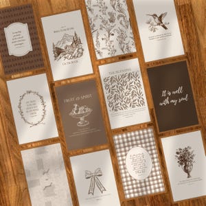 Könnte beinhalten: Eine Sammlung von beigefarbenen und braunen Karten mit verschiedenen Designs und Texten. Zu den Designs gehören florale Muster, ein Kolibri, eine Berglandschaft und eine Obstschale. Die Karten sind auf einer Holzoberfläche angeordnet.