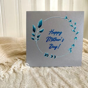 Carte de fête des mères faite main avec une couronne de fleurs bleues