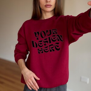 May include: A red sweatshirt with the text "YOUR DESIGN HERE" in black.