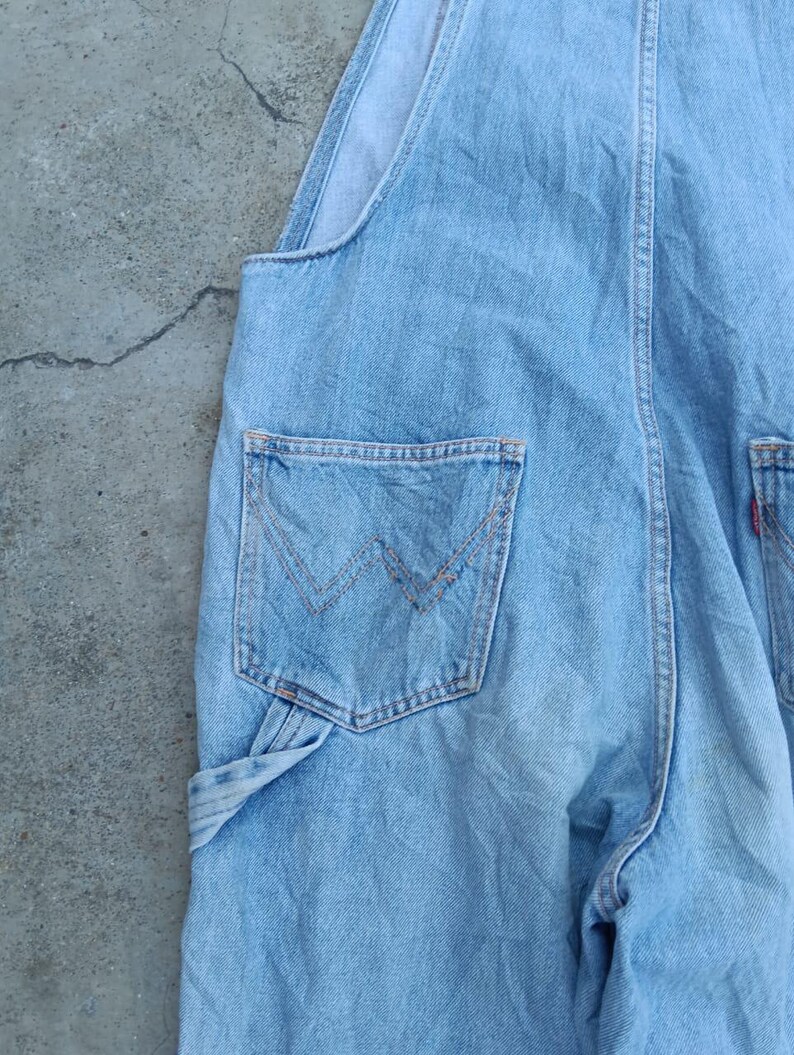 Op de afbeelding: Lichtblauwe denim overall met een klassiek ontwerp. Kenmerken zijn een borstzak aan de voorkant, zijzakken en een achterzak met een kenmerkend gestikt ontwerp. De overall is gemaakt van duurzaam denim materiaal.