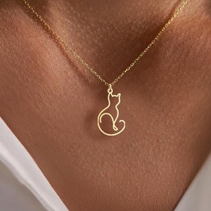 May include: A gold chain necklace with a delicate cat silhouette pendant.