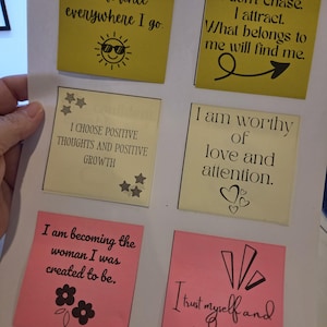 May include: A sheet of six square adhesive notes in yellow and pink, featuring black printed affirmations. The notes include phrases like I radiate confidence everywhere I go, I don't chase. I attract., I choose positive thoughts, and I trust myself.
