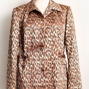 May include: A vintage leopard print coat with a notched collar, long sleeves, and a button-down front. The coat features a brown and black animal print pattern and two front pockets. The coat is displayed on a mannequin.