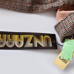 May include: A black and gold label with the text "UNIZNO" in a retro font. A green tag with the text "REMOVE" and the text "N. 420817 UNZARRA" is attached to the label.