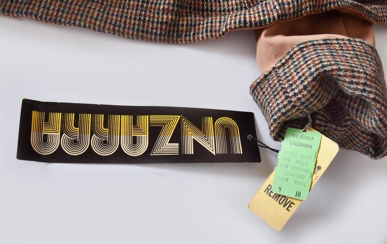 May include: A black and gold label with the text "UNIZNO" in a retro font. A green tag with the text "REMOVE" and the text "N. 420817 UNZARRA" is attached to the label.