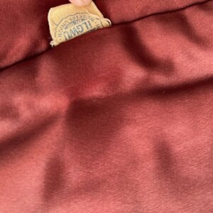 May include: A close-up of a burgundy fabric with a brown label that reads "ILGWU AFL-CIO,  Registered Trade Mark".