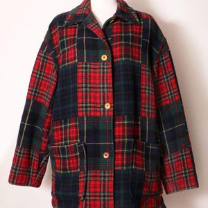 May include: A long-sleeved jacket featuring a patchwork design of red, dark green, and navy blue plaid fabric. The garment includes a classic collar, three light brown circular buttons down the center front, and two large patch pockets at the waist.