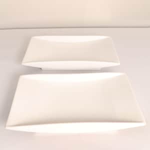 May include: Two white rectangular serving dishes. The dishes have a slightly curved design and are stacked on top of each other. The top dish is smaller than the bottom dish. The dishes are made of a smooth, glossy material.