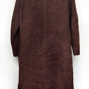 May include: A brown long-sleeved coat with a fur collar. The coat is made of a textured fabric and has a long, flowing silhouette.