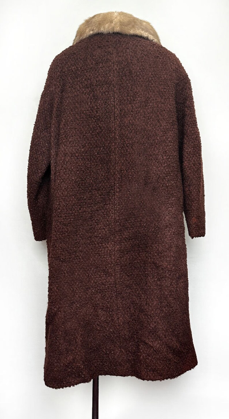 May include: A brown long-sleeved coat with a fur collar. The coat is made of a textured fabric and has a long, flowing silhouette.