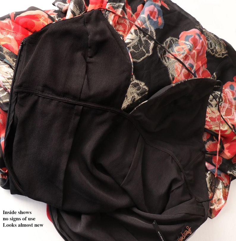 May include: A black dress with a floral pattern in red, gold, and blue. The dress has a black lining and a zipper. The text "Inside shows no signs of use Looks almost new" is visible.