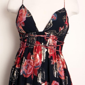 May include: A black floral print dress with a deep V-neck and spaghetti straps. The dress features red and gold floral patterns, with a cinched waist and a flowing skirt. The dress is displayed on a mannequin.