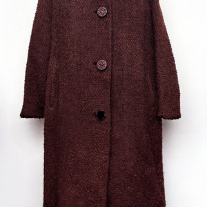 May include: A long, brown wool coat with a fur collar. The coat has a button closure and is lined with a black fabric.