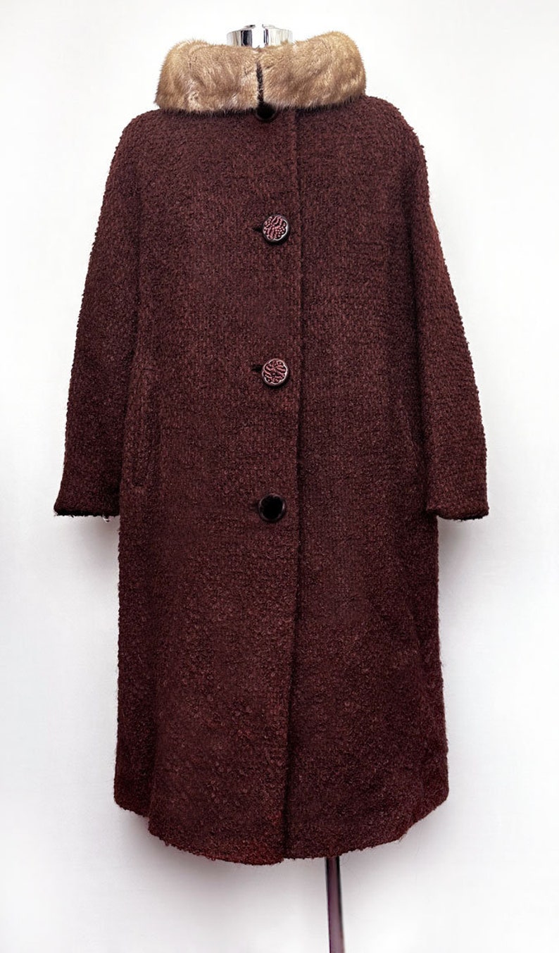 May include: A long, brown wool coat with a fur collar. The coat has a button closure and is lined with a black fabric.