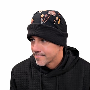 May include: Black beanie with a mushroom print. The beanie has a fold-over cuff.