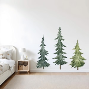 May include: Three watercolor pine tree wall decals in various sizes. The decals are green and feature a realistic design. The decals are shown on a white wall in a living room setting.