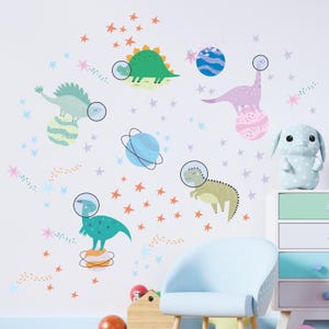 Op de afbeelding: Een set kleurrijke dinosaurus- en planeetmuurstickers voor een kinderkamer. De stickers tonen dinosaurussen met astronautenhelmen en planeten met ringen. De stickers zijn perfect om elke kamer een leuke en fantasierijke touch te geven.