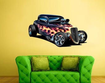 May include: A black hot rod car with flames painted on the side. The car has large chrome wheels and a vintage design. The image is a wall decal, with a green sofa and yellow wall in the background.
