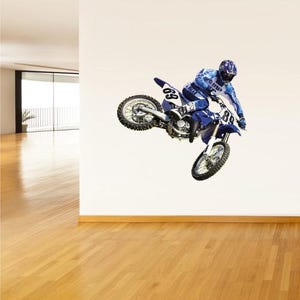 May include: A blue and white Yamaha dirt bike with the number 89 on the front and 69 on the side is shown mid-air. The rider is wearing a blue and white racing suit and helmet. The image is a wall decal.
