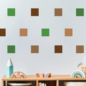 May include: A white wall with brown, green, and tan squares arranged in a pattern. The wall is in a room with a wooden shelf and various toys.