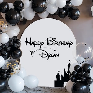 May include: Black and white balloon arch with a white round sign that says "Happy Birthday Dylan" with a silhouette of a castle and a fairy.