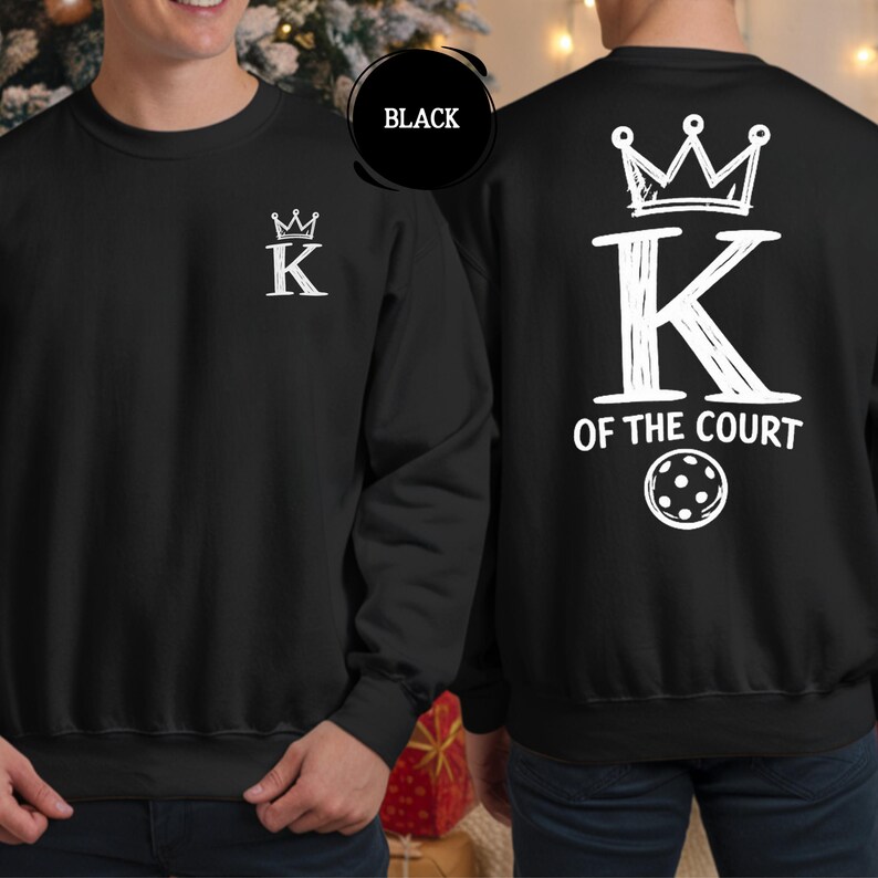 May include: Black sweatshirt with white text and graphics. The front features a crown above the letter "K". The back displays a large "K" with a crown, the words "OF THE COURT", and a pickleball graphic.