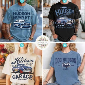 May include: Four t-shirts with car-themed designs. The shirts are light blue, black, cream, and blue. Each shirt features a graphic of a vintage car and text, including "Hudson Hornet," "Doc Hudson," and "Garage."