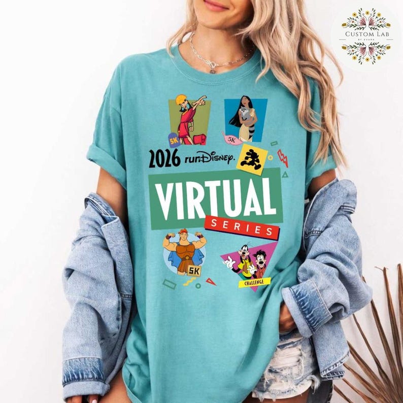 May include: A turquoise t-shirt featuring the text "2026 runDisney VIRTUAL SERIES" with cartoon character graphics. The shirt includes images of Hercules, Moana, and Goofy. The shirt has rolled-up sleeves and is worn with a denim jacket.