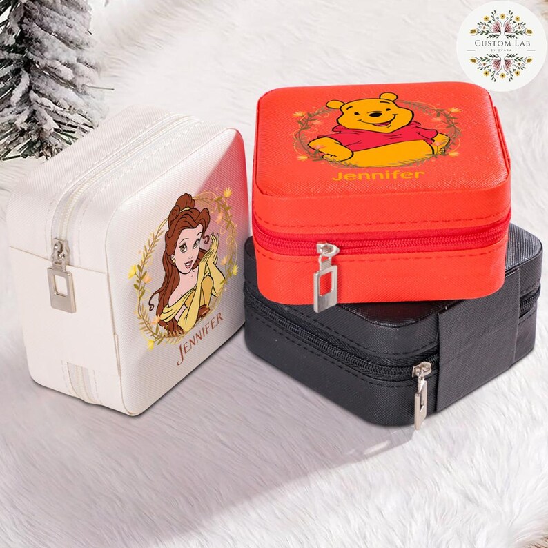 May include: Three square jewelry boxes in white, red, and black. The white box features a princess graphic and the name "Jennifer". The red box has a Winnie the Pooh graphic and the name "Jennifer". The black box is plain.