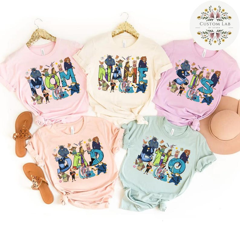 Pu&ograve; includere: Cinque magliette dai colori pastello con le parole "MOM", "NAME", "SIS", "DAD" e "BRO" stampate. Ogni parola &egrave; disegnata con un tema di personaggi dei cartoni animati. Le magliette sono in vari colori pastello, tra cui rosa, crema e blu.