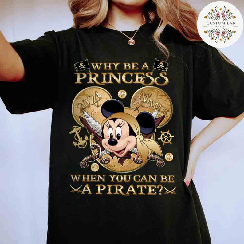 K&ouml;nnte beinhalten: Schwarzes T-Shirt mit einer goldenen Grafik von Mickey Mouse, der als Pirat verkleidet ist. Die Grafik enth&auml;lt den Text "Why be a princess when you can be a pirate?" und "2024" und "Nance".